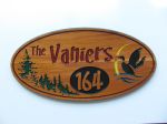 Oval routered wooden sign with address, trees and loon